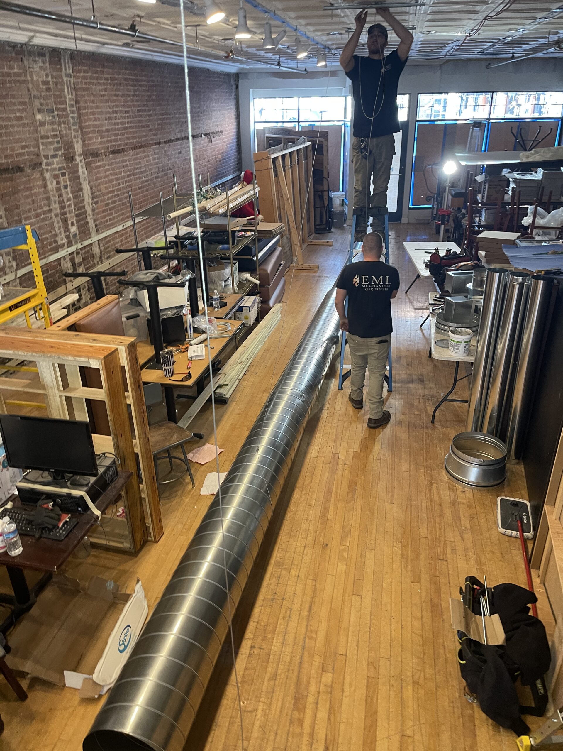 EML Mechanical crew installing long exposed spiral ductwork in a commercial renovation